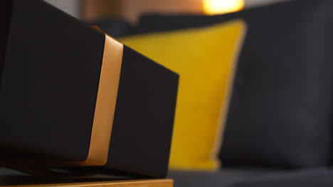 Close-Up-Of-Man-Putting-Down-Gift-Wrapped-Present-From-Table-In-Lounge-At-Home